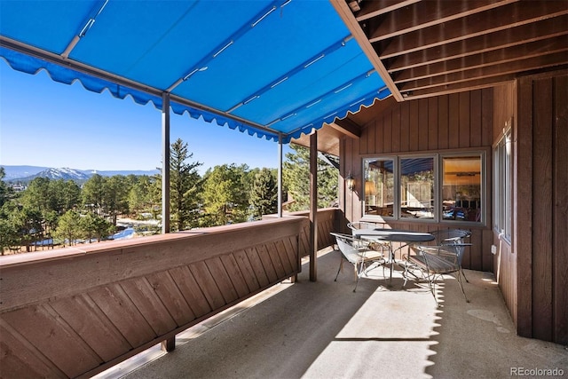 balcony with a sunroom, outdoor dining area, and a mountain view