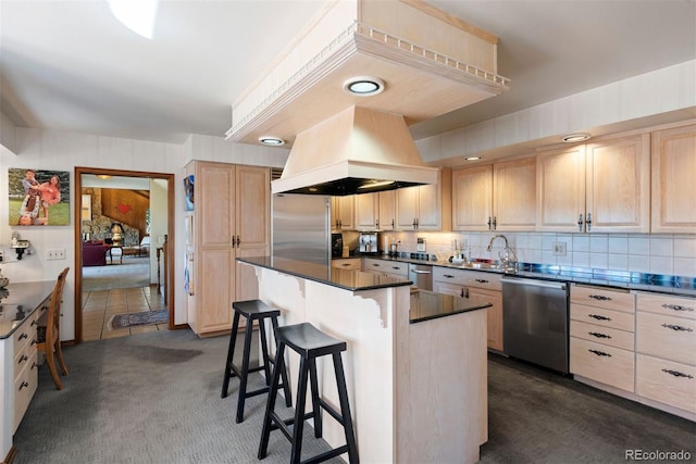 kitchen featuring a breakfast bar area, light brown cabinets, premium range hood, a sink, and appliances with stainless steel finishes