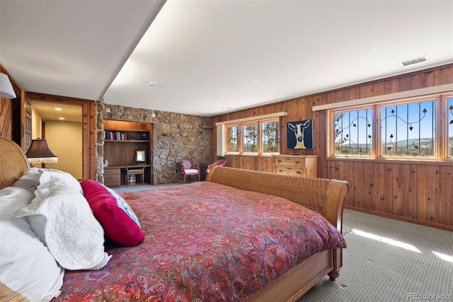 bedroom featuring carpet floors, wooden walls, and visible vents