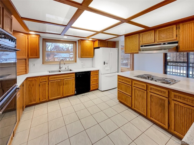 kitchen featuring brown cabinets, light countertops, a sink, under cabinet range hood, and black appliances