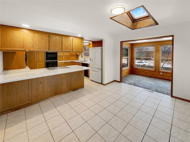 kitchen featuring visible vents, a peninsula, light countertops, white fridge with ice dispenser, and a sink