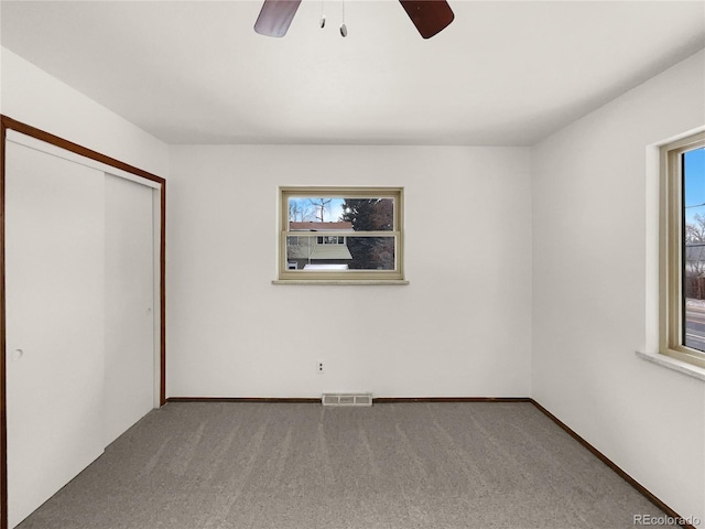 unfurnished bedroom featuring visible vents, carpet flooring, and multiple windows