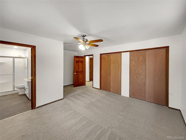 unfurnished bedroom featuring ceiling fan, connected bathroom, light colored carpet, baseboards, and two closets