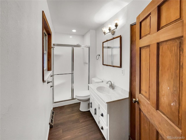 bathroom with toilet, wood finished floors, a shower stall, and vanity