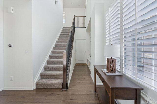 stairway featuring a towering ceiling and hardwood / wood-style floors