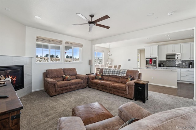 carpeted living room with ceiling fan and a fireplace