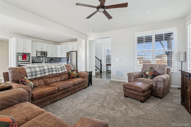 carpeted living room featuring sink and ceiling fan