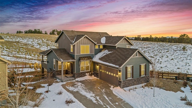 view of front of house featuring fence, concrete driveway, an attached garage, board and batten siding, and stone siding