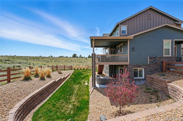 view of property exterior featuring central AC, stone siding, board and batten siding, and a fenced backyard