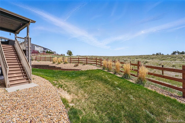 view of yard with stairway, a fenced backyard, and a rural view