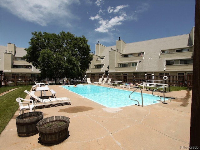 community pool with fence and a patio area