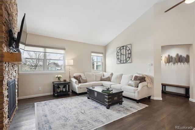 living room featuring dark wood-type flooring, a fireplace, a healthy amount of sunlight, and lofted ceiling