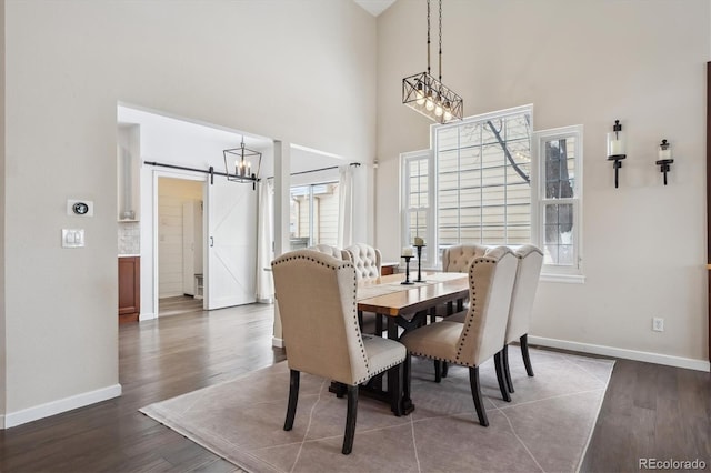 dining area with a barn door, dark hardwood / wood-style flooring, and a high ceiling