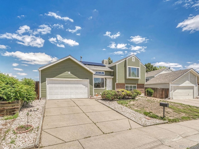 778 S Fairplay Ct, Aurora, CO 80012 - tri-level home featuring brick siding, roof mounted solar panels, driveway, and a garage