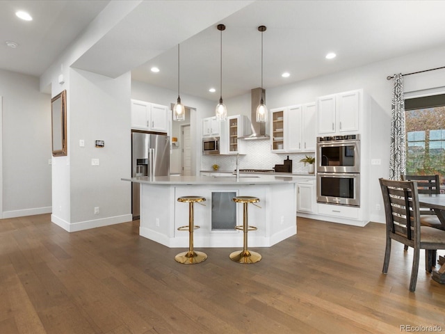 kitchen featuring wall chimney exhaust hood, backsplash, white cabinetry, and stainless steel appliances