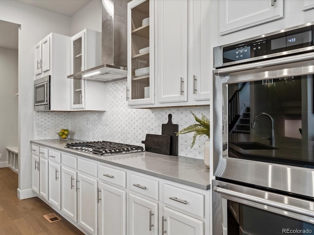 9378 E 60th Pl, Denver, CO 80238 - kitchen featuring white cabinets, wall chimney range hood, and stainless steel appliances