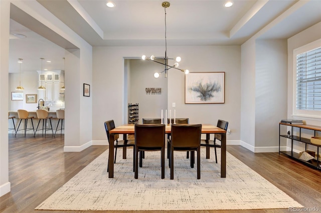 dining room featuring dark wood-style floors, a tray ceiling, and baseboards