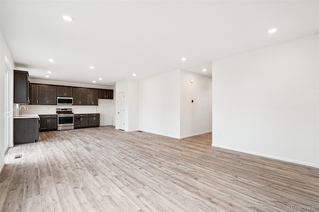 unfurnished living room with light hardwood / wood-style flooring and sink