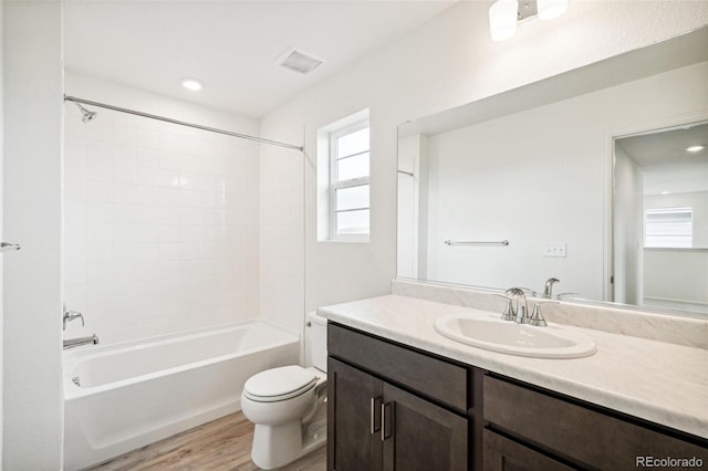 full bathroom featuring toilet, tiled shower / bath, vanity, and wood-type flooring