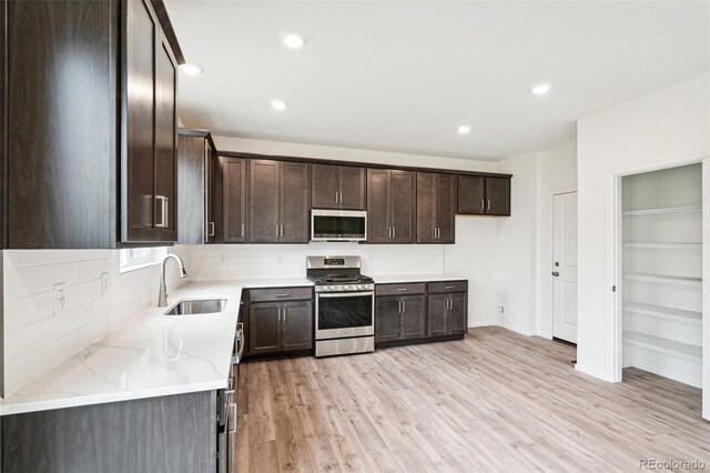 kitchen featuring light stone counters, light hardwood / wood-style flooring, sink, dark brown cabinetry, and stainless steel appliances