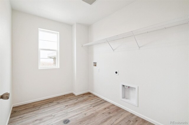 clothes washing area with electric dryer hookup, washer hookup, and light hardwood / wood-style floors