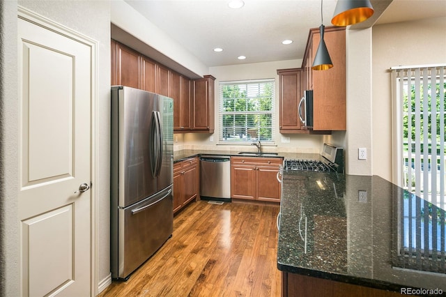 1067 Uinta Way Unit 1067, Denver, CO 80230 - kitchen with appliances with stainless steel finishes, wood finished floors, dark stone counters, brown cabinetry, and recessed lighting