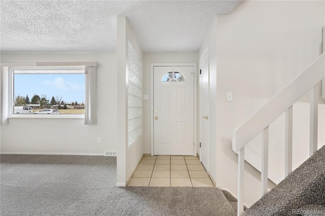 foyer entrance featuring light carpet and a textured ceiling