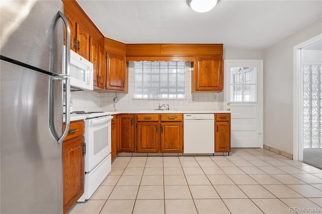 kitchen featuring decorative backsplash, light tile patterned flooring, and white appliances