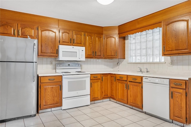 kitchen featuring decorative backsplash, sink, light tile patterned floors, and white appliances