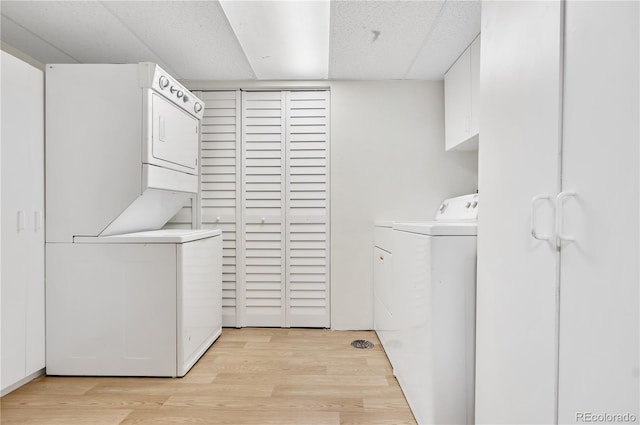 clothes washing area with stacked washing maching and dryer and light wood-type flooring