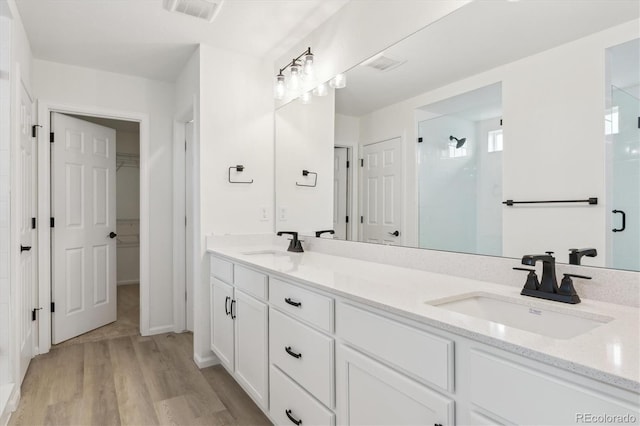 8205 Cokedale Cir, Littleton, CO 80125 - full bath with a stall shower, wood finished floors, a walk in closet, and double vanity