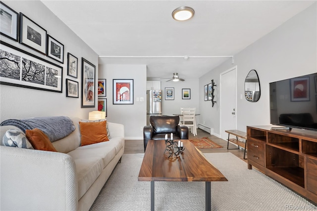 living room with ceiling fan, light hardwood / wood-style floors, and a baseboard heating unit