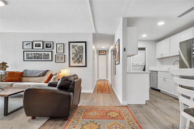 living room with sink, light hardwood / wood-style floors, and stacked washer and clothes dryer