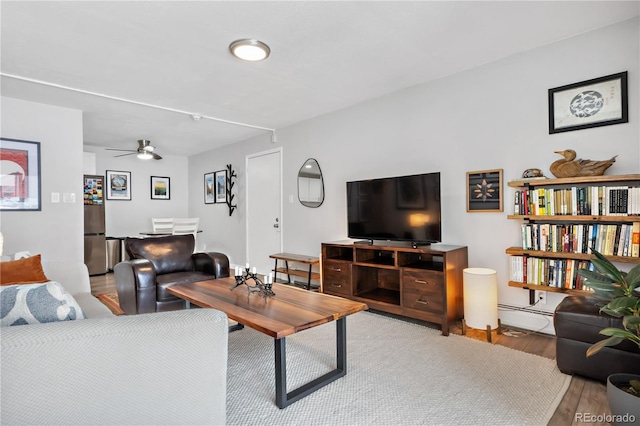 living room with a baseboard heating unit, light hardwood / wood-style floors, and ceiling fan