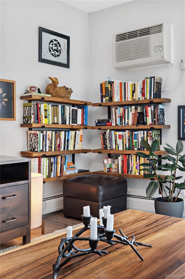 living area featuring hardwood / wood-style flooring and a wall unit AC