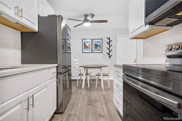 kitchen with white cabinetry, stainless steel appliances, decorative backsplash, and light wood-type flooring