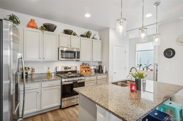 kitchen with white cabinetry, pendant lighting, a breakfast bar area, a kitchen island with sink, and appliances with stainless steel finishes