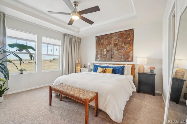 bedroom with ceiling fan, a raised ceiling, and light carpet