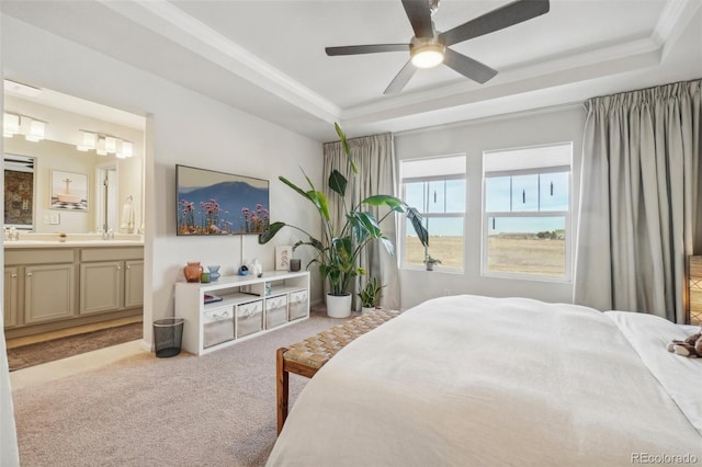 bedroom with ceiling fan, ensuite bath, light carpet, and a tray ceiling