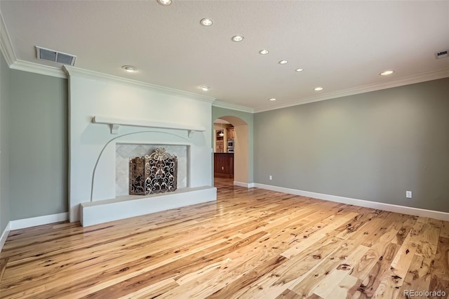 unfurnished living room with arched walkways, crown molding, visible vents, and recessed lighting