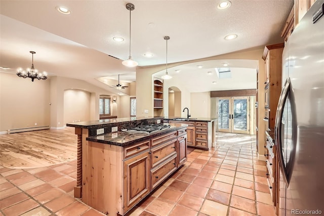 kitchen featuring stainless steel appliances, arched walkways, recessed lighting, decorative light fixtures, and a baseboard radiator