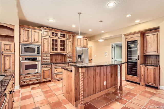 kitchen featuring recessed lighting, glass insert cabinets, appliances with stainless steel finishes, a kitchen island, and a breakfast bar area