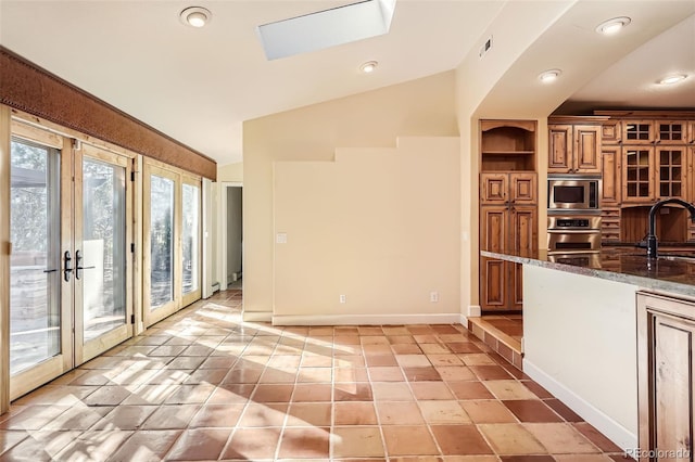 kitchen with a sink, dark stone countertops, visible vents, brown cabinets, and appliances with stainless steel finishes