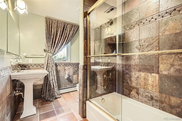 bathroom with a wainscoted wall, tile patterned floors, combined bath / shower with glass door, tile walls, and a baseboard radiator