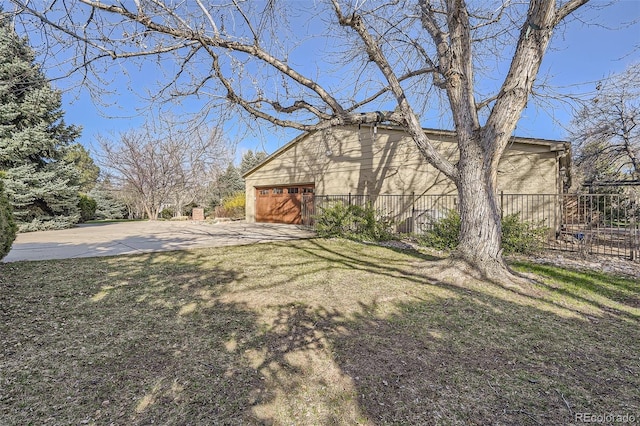 view of yard featuring fence, driveway, and a garage