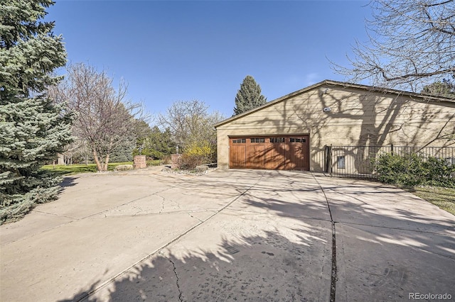 garage featuring driveway and fence