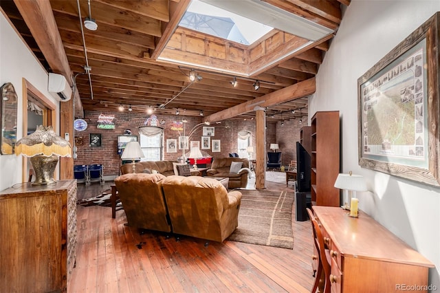 living room featuring brick wall, a wall mounted AC, hardwood / wood-style floors, and rail lighting