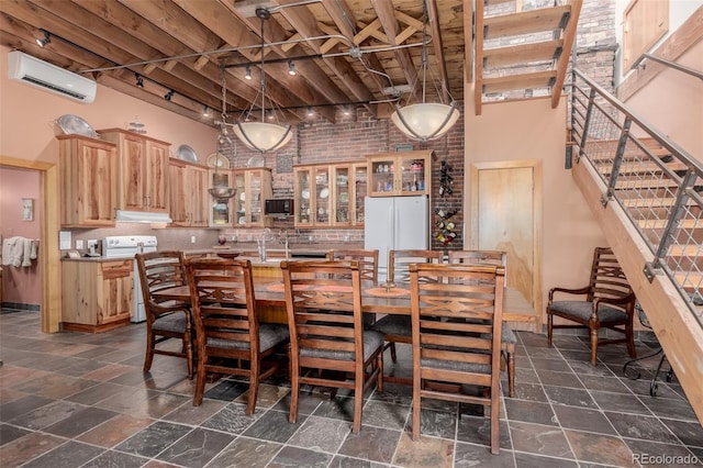 dining area with a high ceiling, brick wall, sink, a wall mounted air conditioner, and track lighting