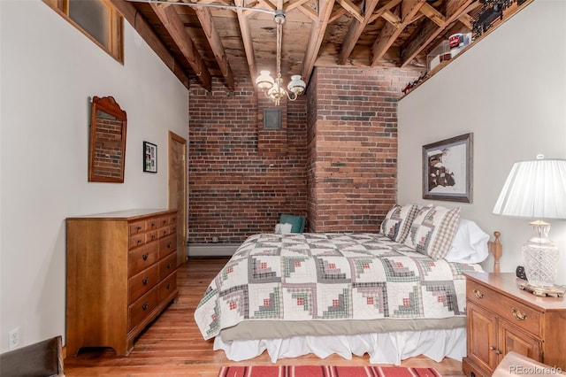 bedroom with wooden ceiling, light hardwood / wood-style floors, brick wall, and beamed ceiling