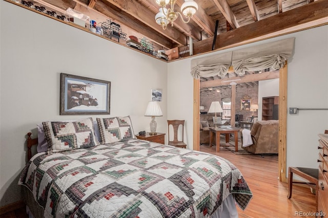 bedroom with a notable chandelier, beamed ceiling, and light hardwood / wood-style flooring